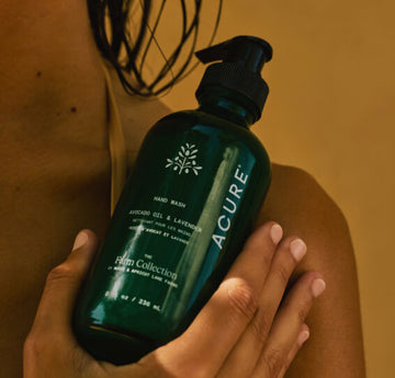 Acure hand wash bottle held by a person with a warm background