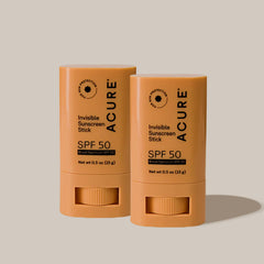 Two Acure Invisible Sunscreen Sticks SPF 50 on a beige background