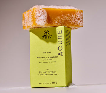 Acure bar soap with a sponge on top against a neutral background