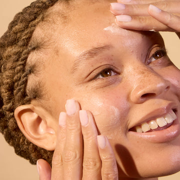 Woman applying Acure's face moisturizer to get smooth, bright and hydrated skin