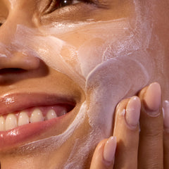Close-up of a person applying a skincare product to their face.