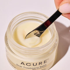 Acure Scar Treatment Balm jar with a spoon scooping out cream