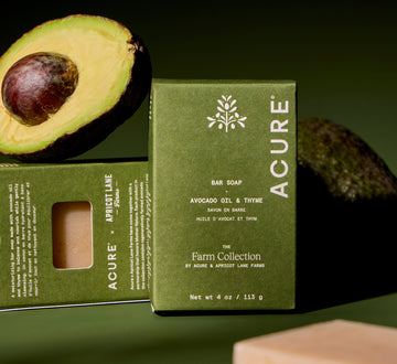 Acure Avocado Oil and Thyme bar soap with an avocado on a green background