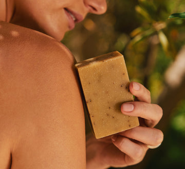 Person holding a bar of soap with a natural background